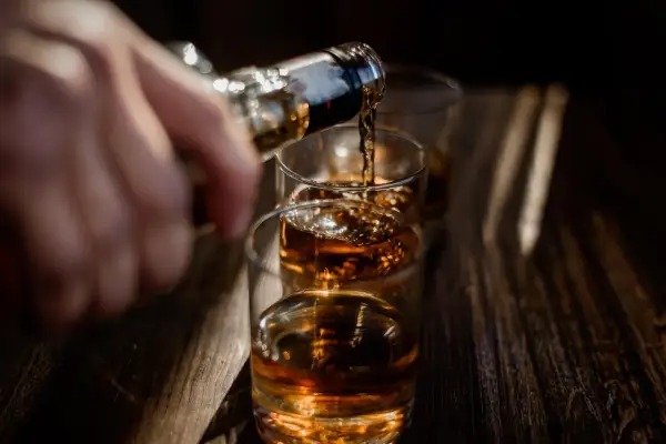 Nalewanie alkoholu do szklanek. Ta scena może symbolizować sprawę w sądzie za picie alkoholu przez nieletnich.