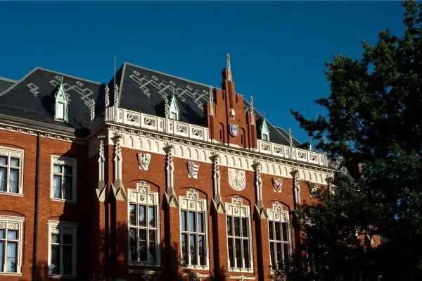 Elegancka fasada jednego z uniwersytetów w Krakowie, z charakterystycznymi detalami architektonicznymi i herbami.