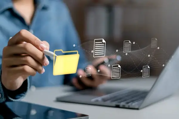 Main d'une personne utilisant un stylet pour interagir avec une icône de dossier jaune, symbolisant la digitalisation des processus et le flux de documents numériques.
