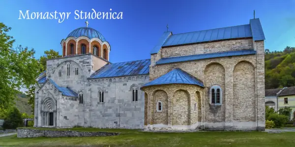 Kamienne mury i niebieskie dachy monastyru Studenica wznoszą się na tle zielonych wzgórz.