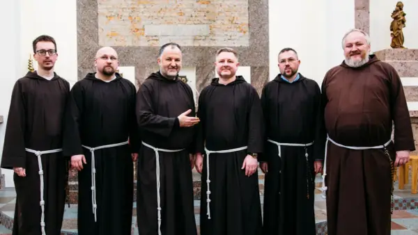 Sześciu mężczyzn w brązowych habitach, każdy z białym sznurem przepasanym w pasie. To grupa kapucynów.