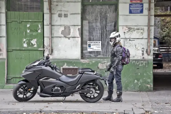 Motocyklista w kasku obok swojego futurystycznego Honda NM4 Vultus.