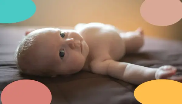 Un bebé de 2 meses, con ojos curiosos, yace boca arriba. Parece que este pequeño no duerme, ¡sus ojitos están bien abiertos!