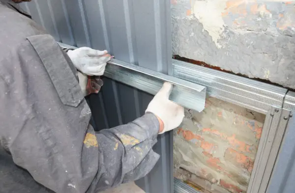 Arbeiter montiert Metallprofile für die Abdichtung des Hauses.