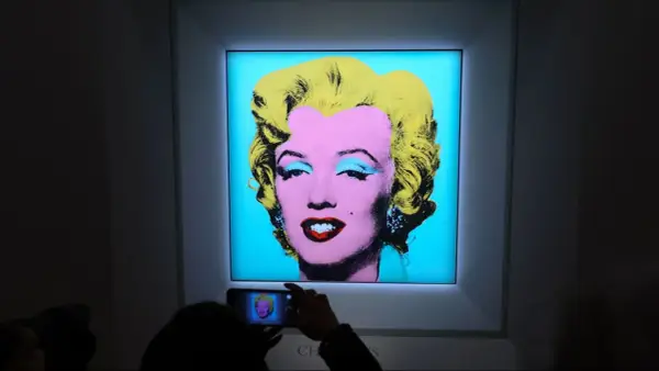 A person photographs Andy Warhol's iconic Marilyn Monroe printmaking, capturing the vibrant colors and pop art style.