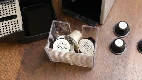 Pojemnik z kapsułkami do Nespresso, obok ekspresu i tacki na zużyte kapsułki. Czas na odkamienianie!