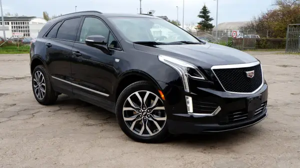 Czarny Cadillac XT5 z chromowanymi detalami i charakterystyczną atrapą chłodnicy stoi na betonowym placu.