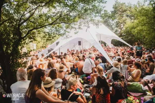 Tłum ludzi siedzi pod białym namiotem na jednym z letnich festiwali w Polsce.