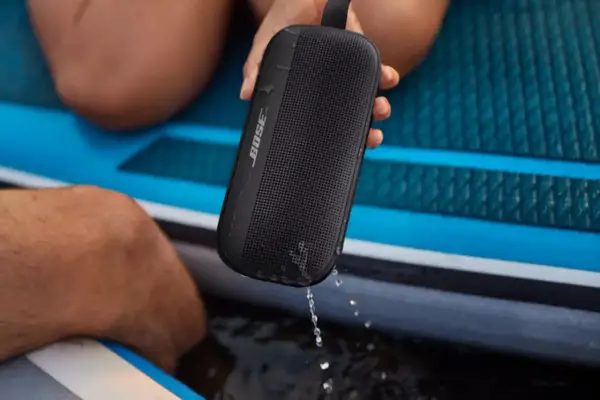 Enceinte Bose noire, étanche IPX4, éclaboussée par la pluie sur un paddleboard.
