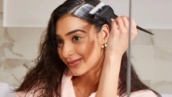 Mujer aplica producto para aclarar pelo castaño oscuro sin decolorar.