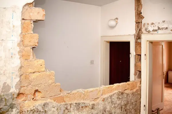 Rozbiórka budynku, odsłonięta wspólna ściana z cegieł między drzwiami.