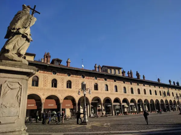 Statua e portici decorati in Piazza Ducale, un luogo imperdibile tra le cose da vedere a Vigevano.