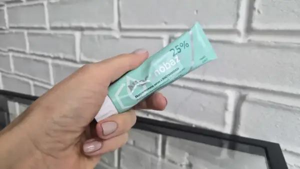Dłoń trzyma tubkę serum niacynobaza 25%. Wiele pozytywnych opinii o tym produkcie.