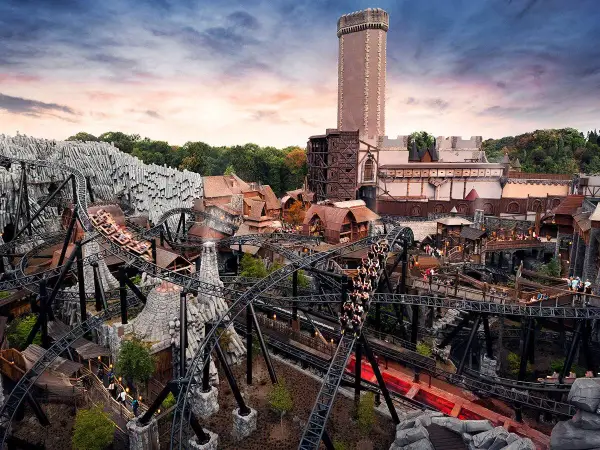 Achtung, **Phantasialand Geburtstagskinder**! Die Achterbahn rast durch eine mittelalterliche Kulisse mit Burg und Felsen.