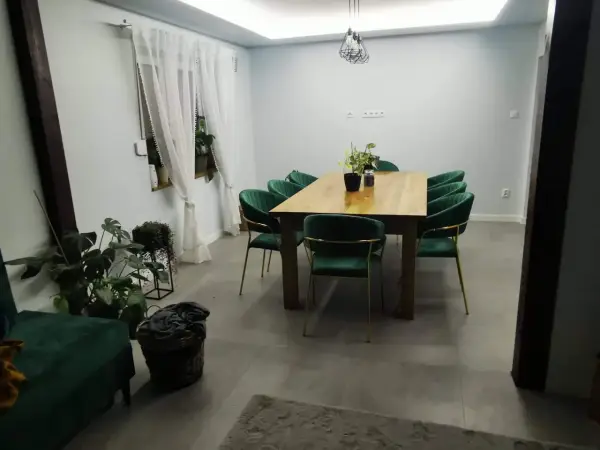 Elegancki salon w stylu glamour z zielonymi aksamitnymi krzesłami i drewnianym stołem.
