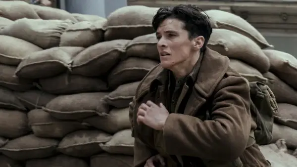 En ung soldat, en del av rollistan i Dunkirk, gömmer sig bakom sandsäckar.