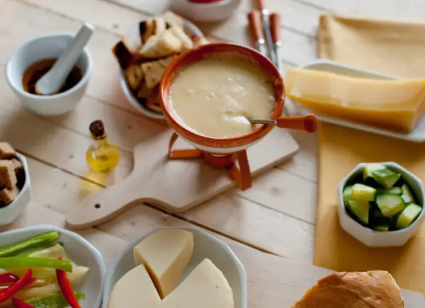 Pyszne fondue serowe z dodatkami: pieczywo, warzywa i kawałek sera. Idealny wybór, jaki ser do fondue?