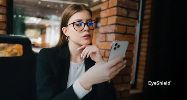 Kobieta w okularach z niebieskimi filtrami przegląda telefon. Różne rodzaje okularów mogą chronić wzrok.