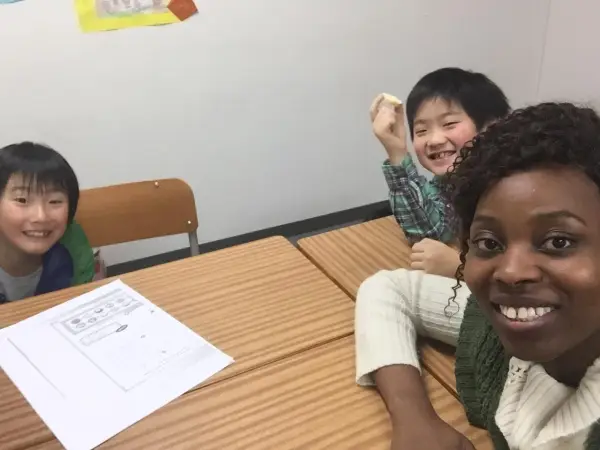 Fröhliche Kinder lernen Englisch. Eine Lehrerin gibt Nachhilfe auf Englisch.