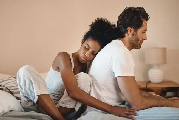 Un couple assis dos à dos sur un lit, l'air distant. On ne peut plus se parler sans s'engueuler.