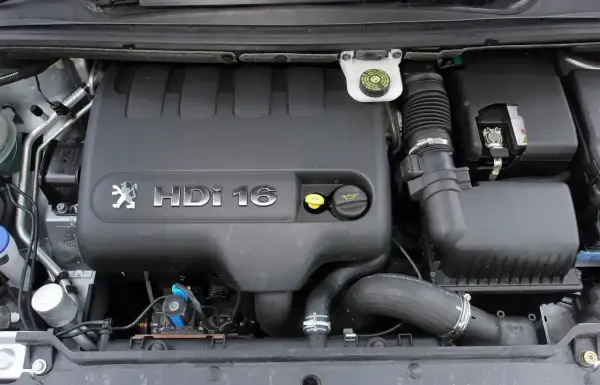 Silnik Peugeot 307 2.0 HDi 16V. Widoczny czarny plastikowy kolektor, zbiorniczek płynu hamulcowego i elementy układu dolotowego.