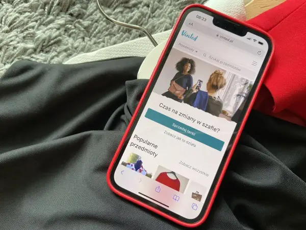 Telefon z aplikacją Vinted leży na ubraniach. Wygląda na to, że portfel Vinted nie działa, bo nie można nic sprzedać.
