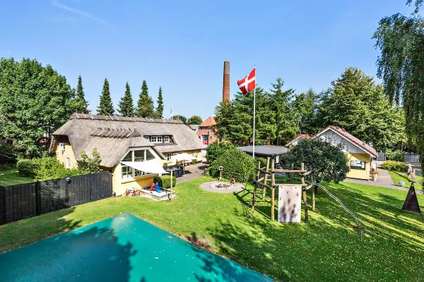 En idyllisk campingplats i Billund med halmtak, lekplats och danska flaggan vajande stolt.