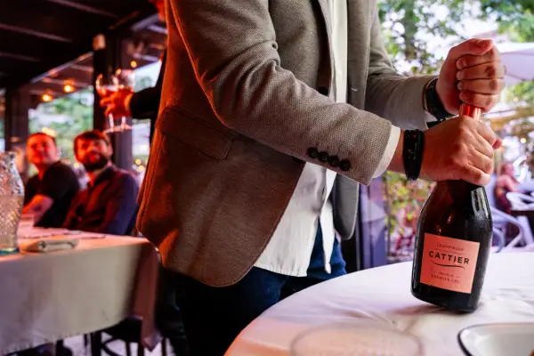Mężczyzna otwiera butelkę szampana Cattier. Różnica między prosecco, cavą i szampanem tkwi w metodzie produkcji.