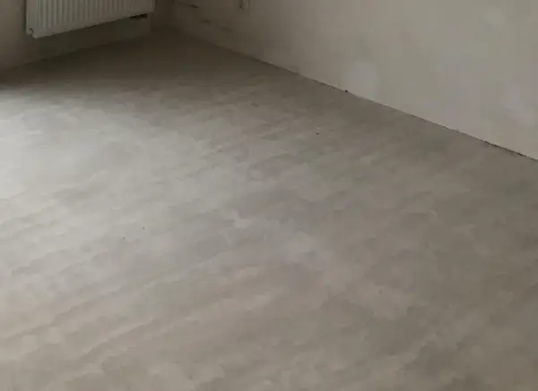 Świeżo wylana, szara krzywa wylewka samopoziomująca na podłodze, gotowa na dalsze prace wykończeniowe.