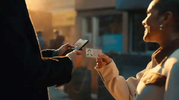 Osoba trzyma telefon z napisem "Approved" i kartę pobytu. Szybka pożyczka na kartę pobytu.