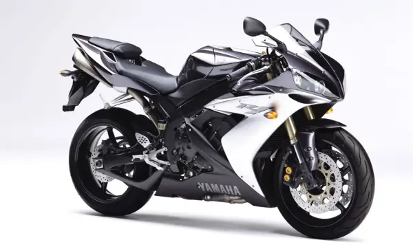 Sportowy motocykl Yamaha R1, jedna z wielu generacji, w kolorze czarno-białym, prezentuje się dynamicznie na białym tle.