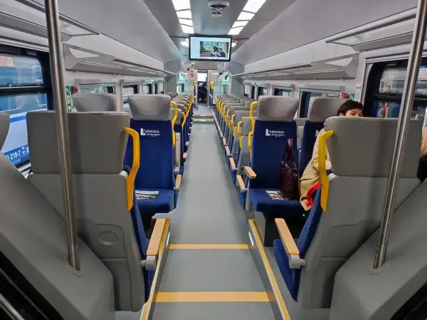 Wnętrze szynobusu na trasie Lublin - Zamość. Puste, niebieskie siedzenia z żółtymi uchwytami czekają na pasażerów.