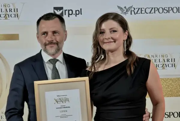 Mężczyzna i kobieta odbierają nagrodę w ramce z napisem "Ranking Kancelarii Prawniczych".