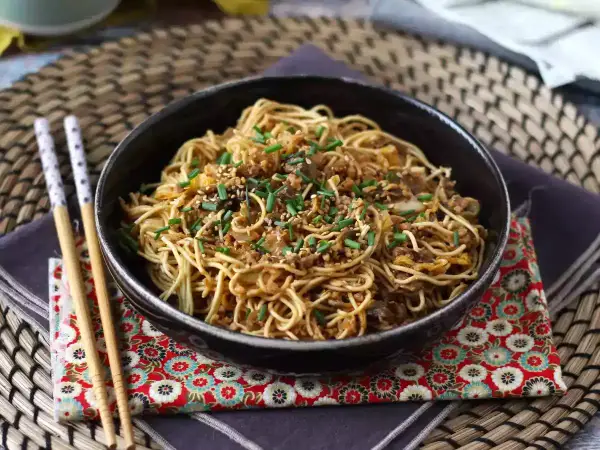 En skål med nudlar, köttfärs och grönsaker, toppad med sesamfrön och gräslök. Ett perfekt wok recept för en snabb middag.