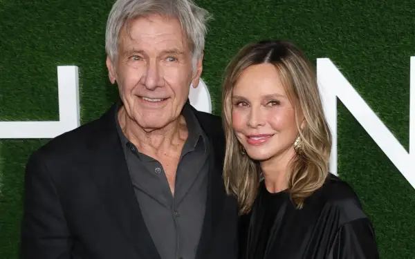 Harrison Ford z żoną Calistą Flockhart na tle zielonej ściany z białymi literami.
