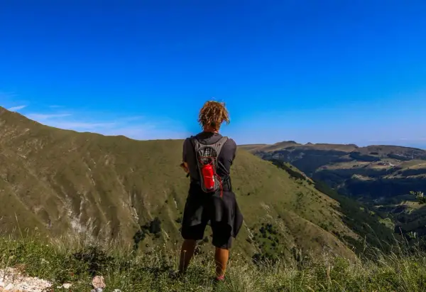 Persona con zaino ammira il panorama durante un trekking di 3 giorni nei Monti Sibillini.