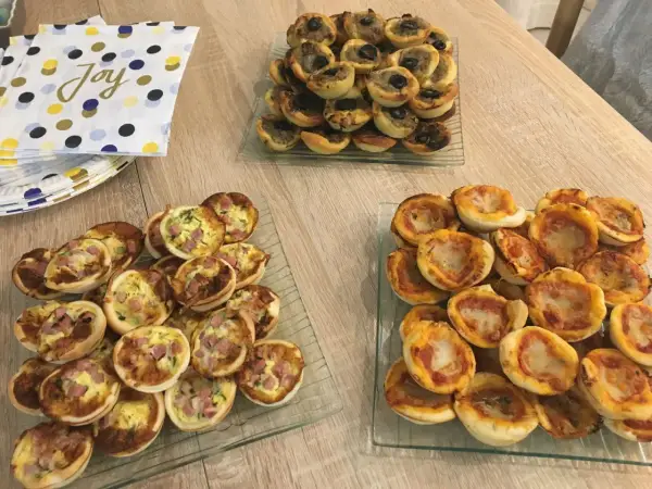 Plateaux de mini-pizzas et quiches, parfaits pour une idée repas crémaillère conviviale.