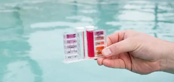 Testeur de piscine mesurant le chlore et le pH. La couleur rouge indique un niveau de chlore élevé, suggérant qu'il faut enlever le chlore de l'eau.
