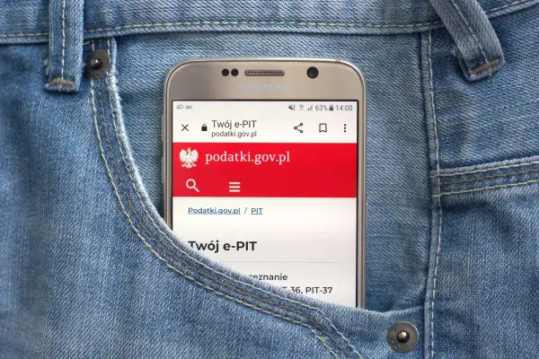 Telefon w kieszeni dżinsów wyświetla stronę podatki.gov.pl, gdzie można sprawdzić, jak zaokrąglić podatek od najmu.