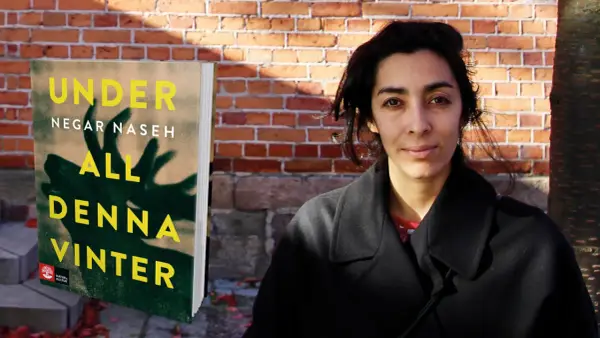 Negar Naseh poserar bredvid sin bok "All denna vinter".