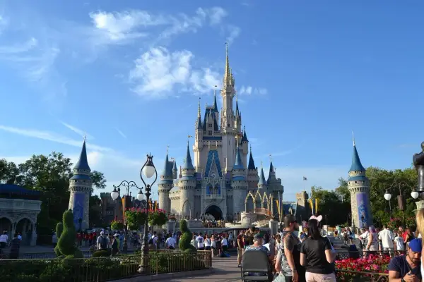Tłum ludzi spaceruje przed zamkiem w Disneylandzie, gdzie marzenia stają się rzeczywistością.