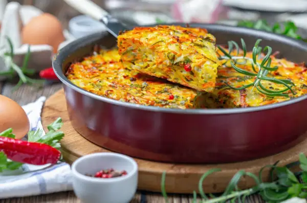 Pyszna, kolorowa zapiekanka warzywna z ziołami – idealna zdrowa kolacja. Widać jajka, papryczkę chili i rozmaryn.