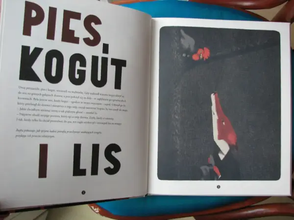 Otwarta książka z tekstem o psie i kogucie, a obok ilustracja lisa i koguta. Bajka uczy, jak sprytni ludzie, jak w tej opowieści z ezopem, potrafią przechytrzyć wrogów.