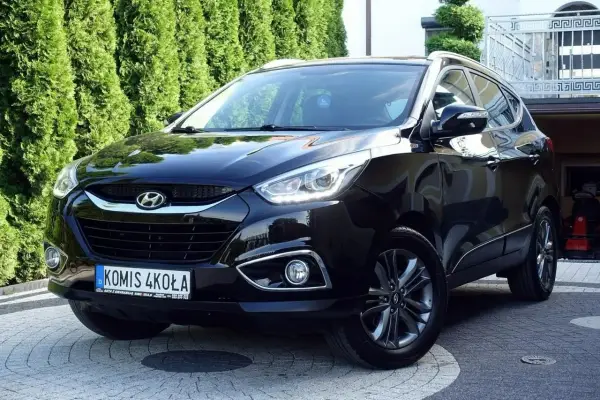 Czarny Hyundai ix35 2.0 benzyna + LPG, lśniący na podjeździe przed zielonym żywopłotem.