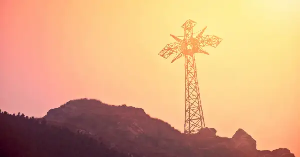Krzyż na Giewoncie, symbol Tatr, wznosi się na tle zachodzącego słońca. Jego budowa to odpowiedź na potrzebę upamiętnienia papieskiej wizyty.