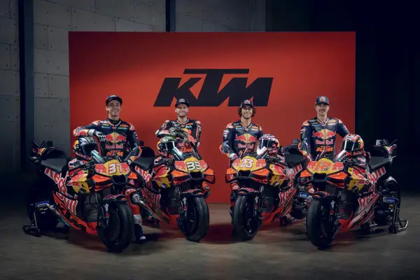 Pilotos de MotoGP KTM posan con sus motos de carreras naranjas y negras, listas para la competición.