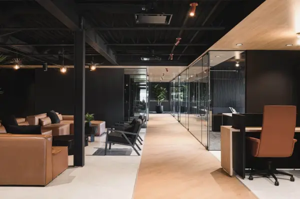 Un espace de travail innovant avec des canapés en cuir, des chaises modernes et des bureaux vitrés.