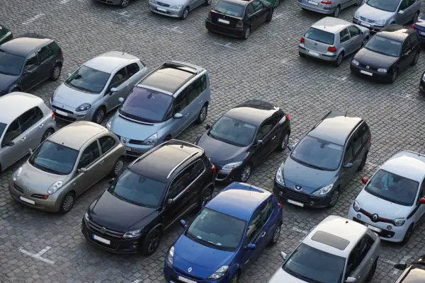 Na parkingu stoi wiele samochodów. Kto to komisant? Może to osoba, która właśnie kupuje lub sprzedaje jeden z tych pojazdów.