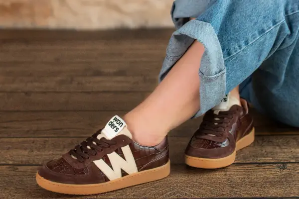 Brązowe buty damskie z krokodylim wzorem i beżowym logo "Wonders" świetnie komponują się z jeansami.