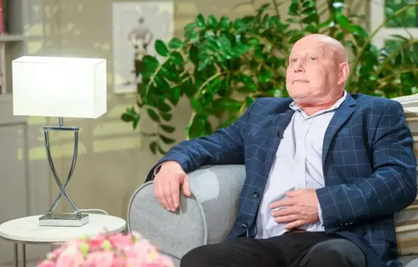 Krzysztof Jackowski w okryciu w kratę, oparty o sofę, jakby snuł najnowsze przepowiednie.